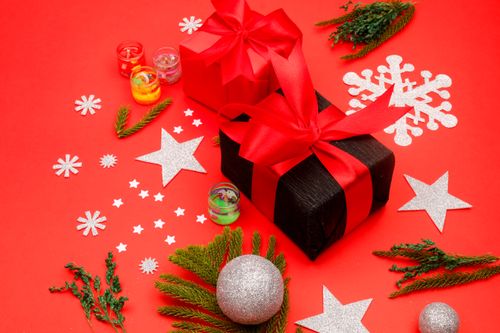 Free Colorful Christmas gifts adorned with ribbons on a red background with decorative elements. Stock Photo