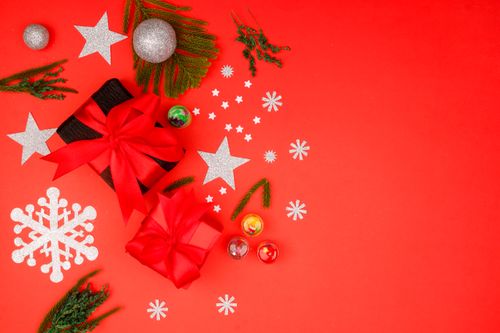 Free Top view of Christmas gifts with red ribbons, ornaments, and silver cutouts on a red background. Stock Photo