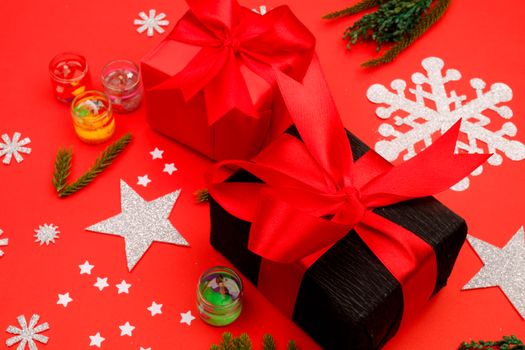 Bright holiday gifts wrapped with red ribbons surrounded by festive decorations on a red background.