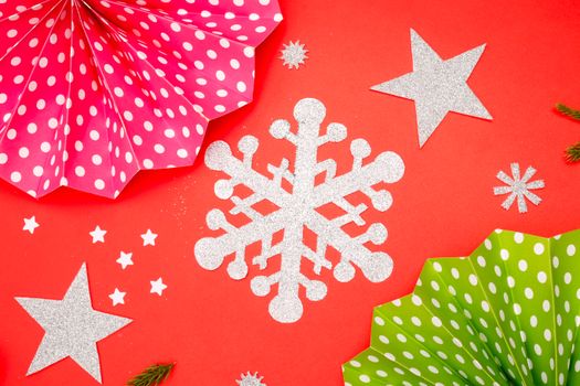 Colorful paper cutout decorations on a red background with stars and snowflakes.