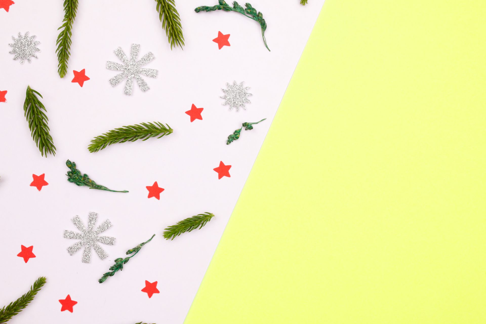 Top view of holiday decorations with spruce branches and stars on colored background, perfect for Christmas themes.