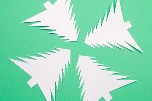 Free Artistic paper cutouts of Christmas trees on a green background, perfect for creative holiday designs. Stock Photo