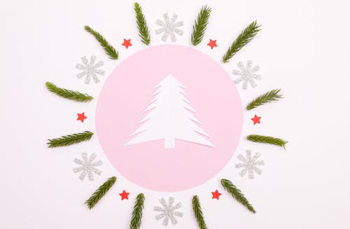 A White Christmas Tree Paper Cutout Surrounded with Green Leaves , Snowflakes and Stars