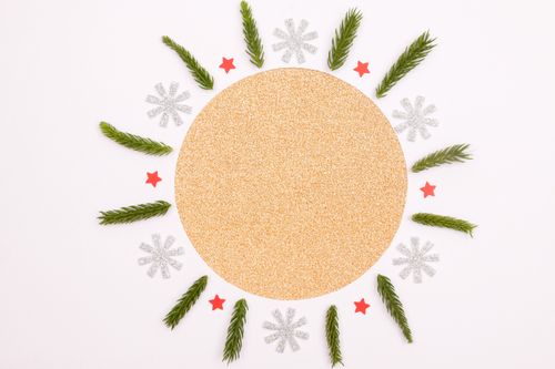 Free A festive Christmas-themed flat lay with pine leaves, stars, and snowflakes on a gold circle backdrop. Stock Photo