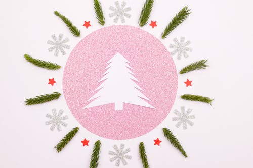 A White Christmas Tree Paper Cutout Surrounded with Green Leaves , Snowflakes and Stars
