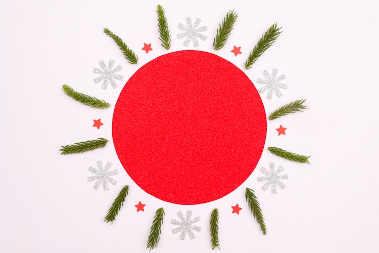 A Red Circle Surrounded By Snowflakes And Leaves Of Qa Christmas Tree