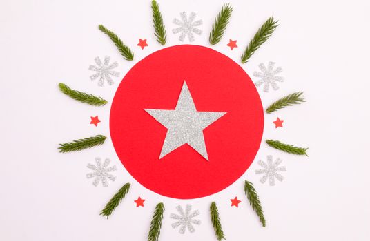 Christmas-themed flat lay with red and silver stars, green needles, and snowflakes on a white background.