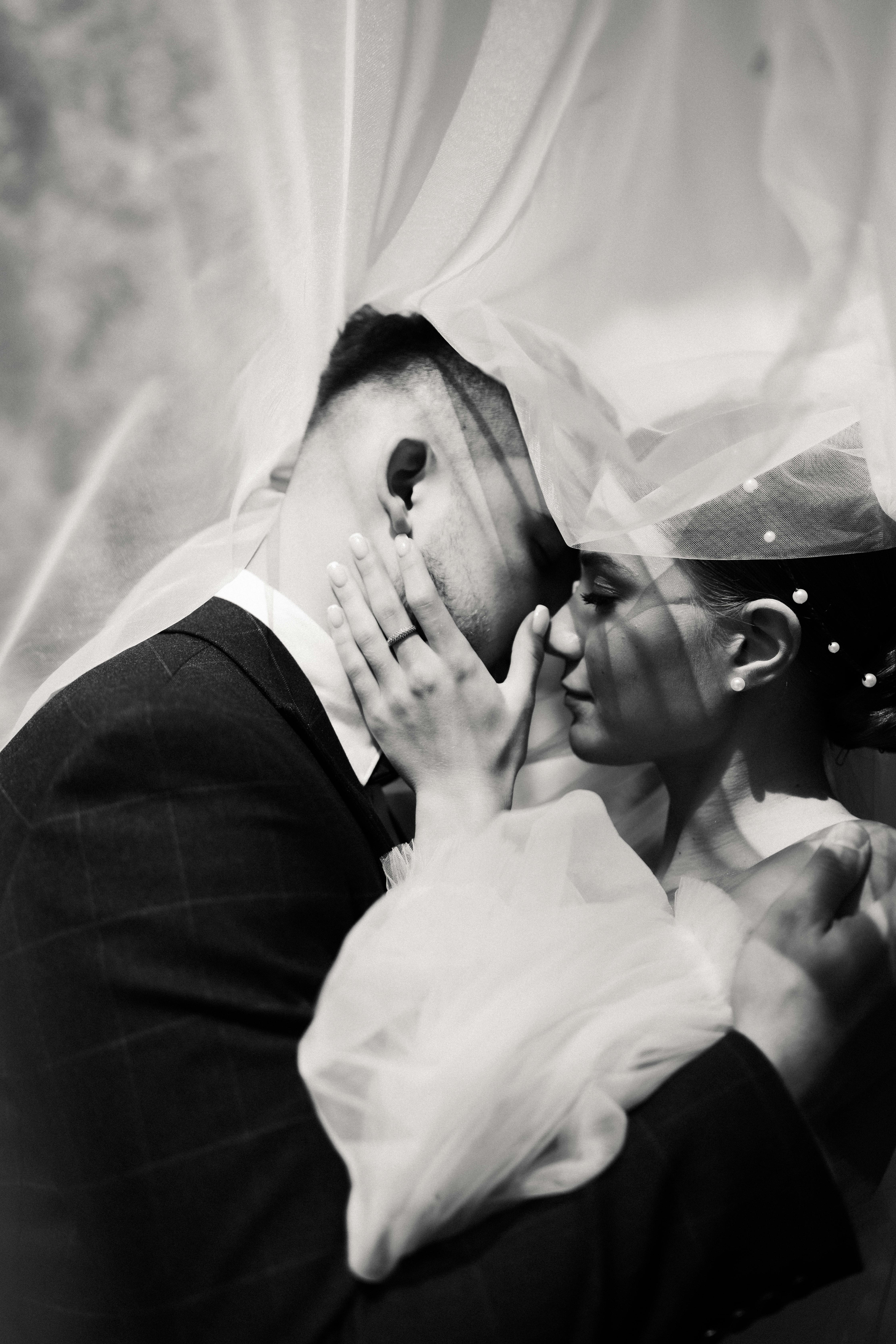 Intimate black and white portrait of a bride and groom sharing a tender moment.