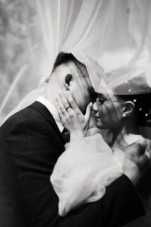 Free Intimate black and white portrait of a bride and groom sharing a tender moment. Stock Photo