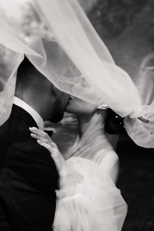 Free A tender moment captured as a bride and groom share a kiss under the veil. Stock Photo