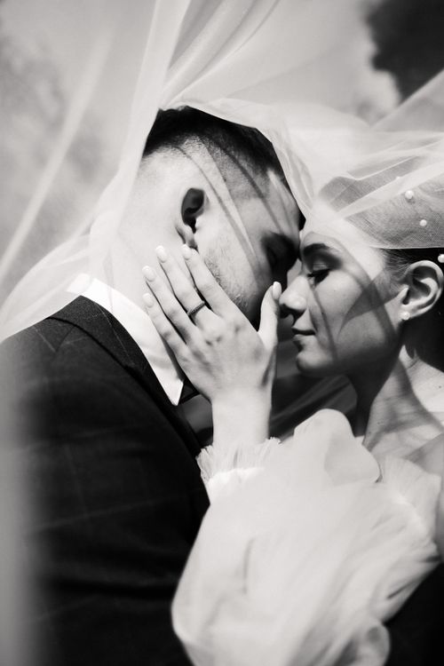 Free Intimate grayscale portrait of a couple embracing under a veil, capturing love and affection. Stock Photo