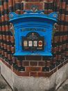A Blue Post Box on Brown and Black Wall