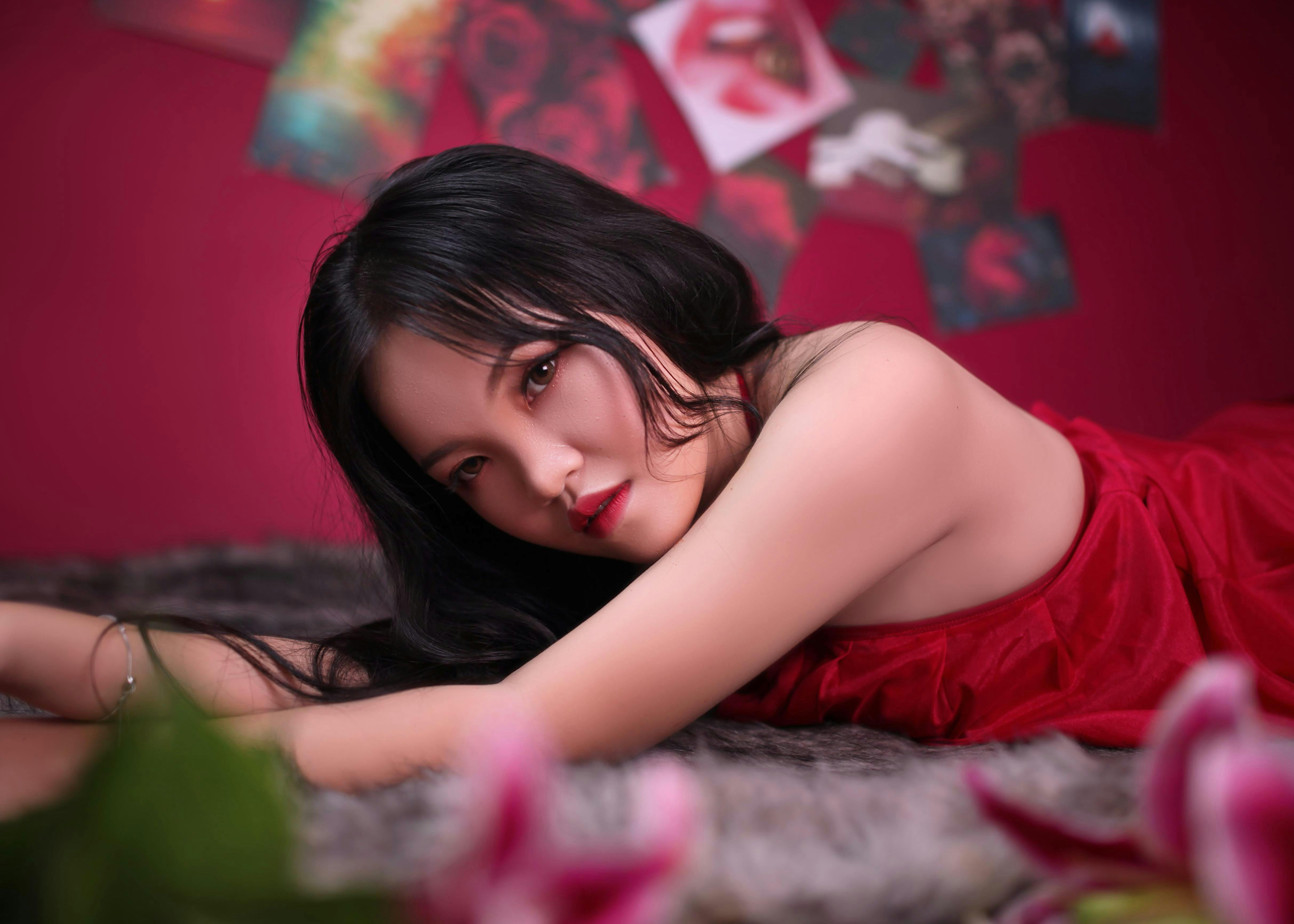 Artistic indoor portrait of an adult woman lying on a fuzzy surface, surrounded by red hues.