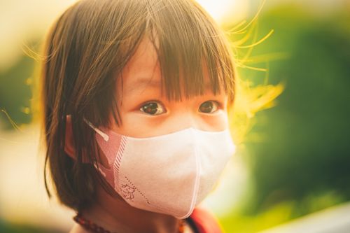 Free A close-up portrait of a child wearing a face mask outdoors, highlighting pandemic life. Stock Photo