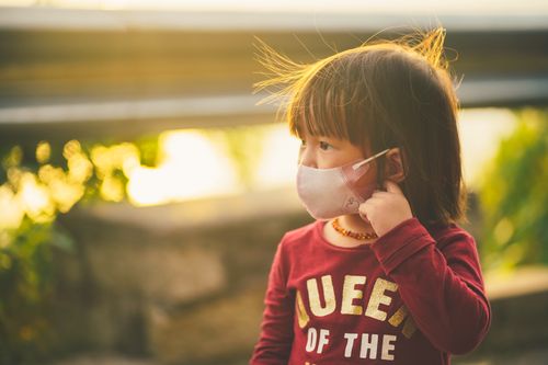 Free Portrait of a young girl wearing a face mask outdoors during sunset, capturing a serene moment. Stock Photo