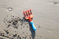 Blue and Orange Plastic Hair Comb on Gray Sand