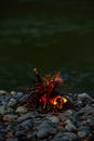 Burning Wood on Gray Rocks Near Body of Water