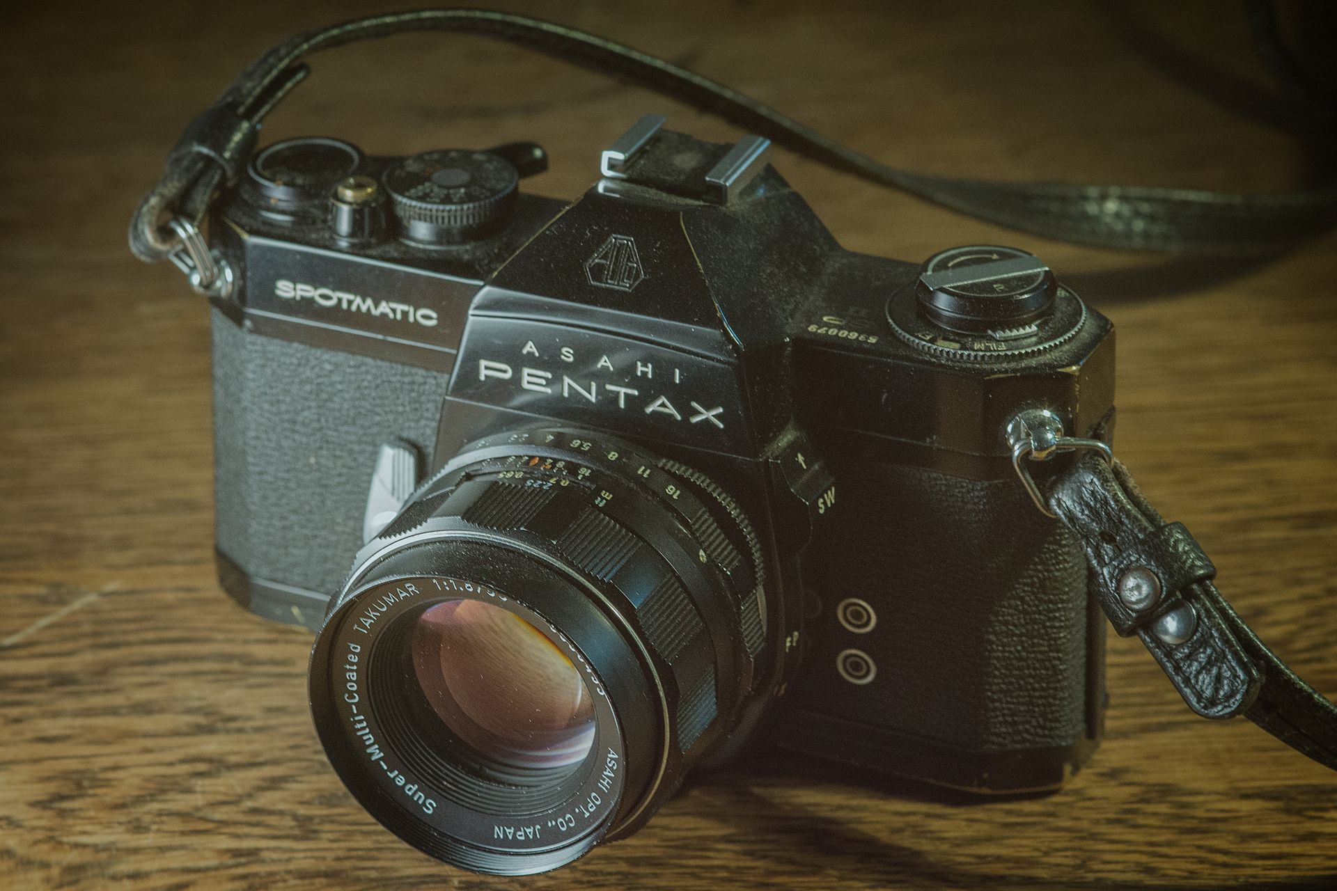 Close-up of a vintage Asahi Pentax Spotmatic analog camera on a wooden surface.