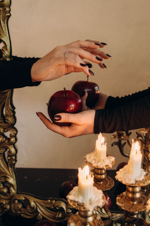 Free Close-up of hands with apples near candles reflecting in a vintage mirror, creating a warm and mysterious atmosphere. Stock Photo