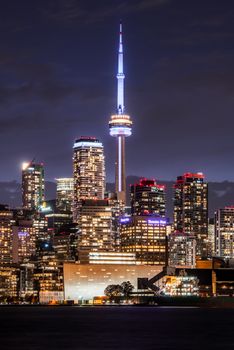 Illuminated view of Toronto's CN Tower against the city skyline at night, showcasing urban beauty.