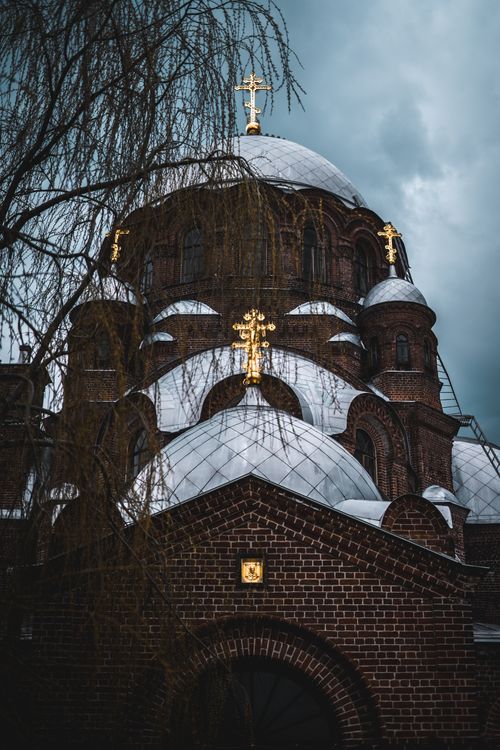 Free Dramatic view of a Gothic cathedral's domes adorned with golden crosses, under a moody sky. Stock Photo