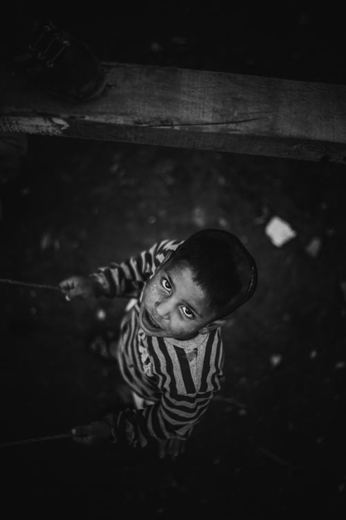 Free A black and white high-angle shot of a boy looking upward, creating a dramatic and emotive scene. Stock Photo