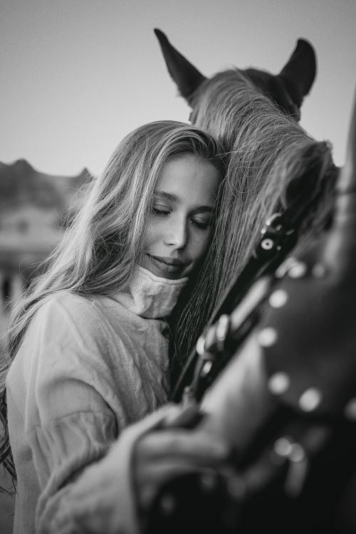 Free A woman lovingly hugs a horse, showcasing a bond in a serene black and white scene. Stock Photo
