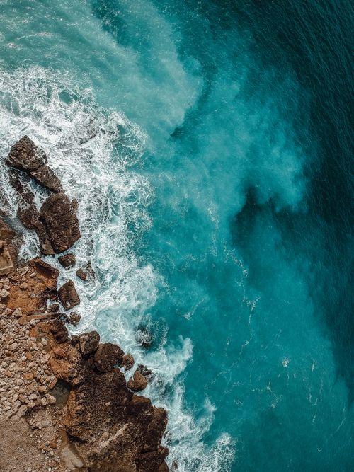 Free Stunning aerial view of waves crashing against Lebanon's rocky coast in vibrant turquoise water. Stock Photo