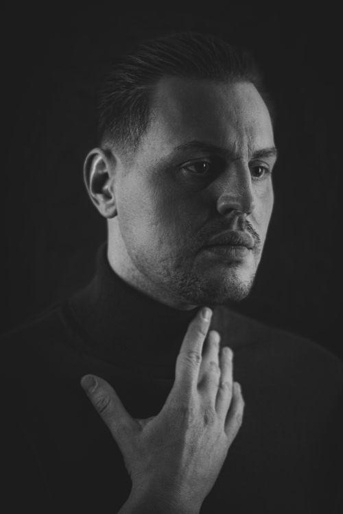 Free Black and white studio portrait of a man with hand on chin, exuding mystery and contemplation. Stock Photo