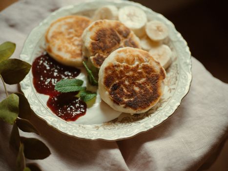 A lovely plate of homemade pancakes with banana slices and raspberry jam, perfect for breakfast.