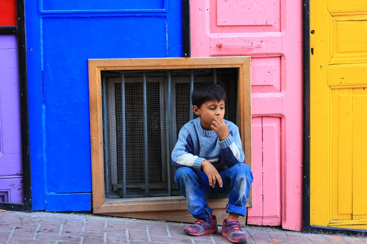 Boy Sitting On Sidewalk