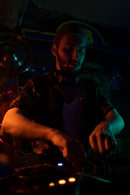 Free A DJ mixes tracks in a dimly lit club, creating a vibrant and moody atmosphere. Stock Photo