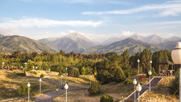 A beautiful mountain park with pathways, trees, and lampposts under a clear sky.