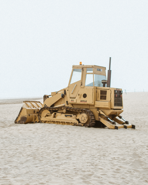 Free A bulldozer parked on a sandy beach in Agadir, Morocco with a misty backdrop. Stock Photo