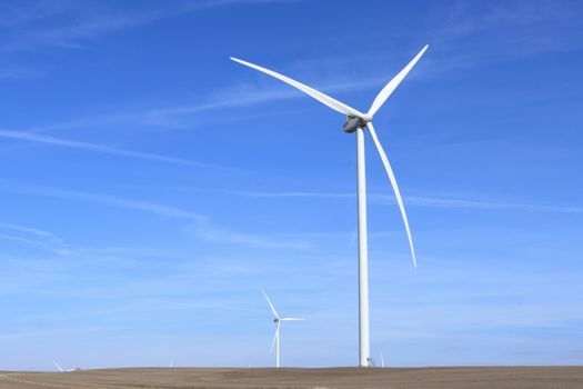 Wind turbines under a clear blue sky symbolize clean energy and sustainability.