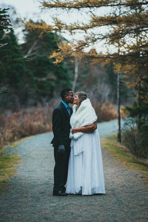 Free Newlyweds Kissing on Forest Path Stock Photo