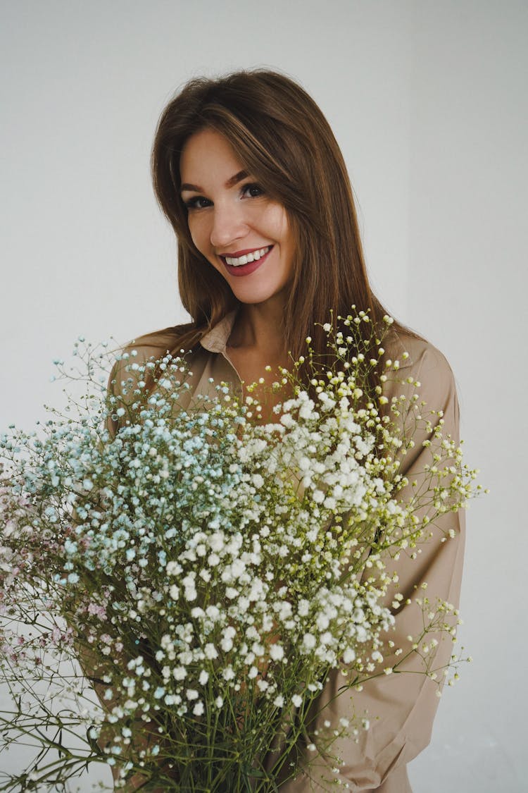 Woman With Long Brown Hair Holding Massive Bunch Of White Tiny Flowers