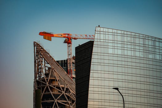 A towering crane at a construction site next to a modern skyscraper, capturing urban development.