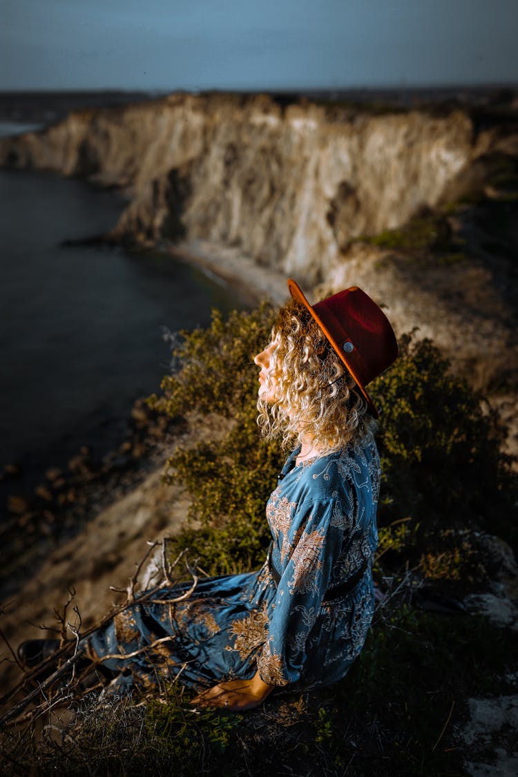 Woman Sitting On Top Of Cliff