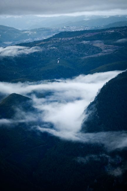 A stunning aerial view showcasing fog and clouds enveloping majestic mountains.