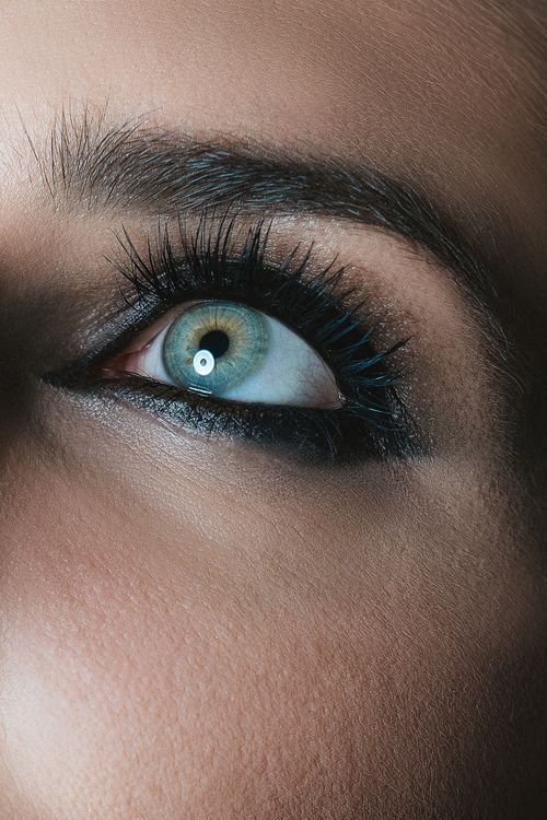 Free Detailed close-up of a woman's green eye with dramatic makeup and lashes. Stock Photo