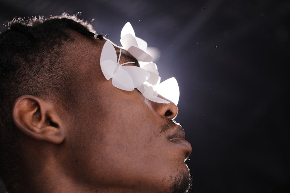 Close-up portrait of a man with paper butterflies on his face, creating a surreal artistic effect.