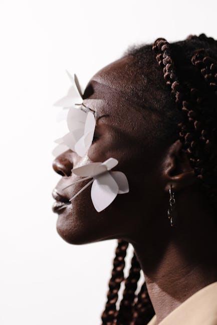 Close-up side view of an African American woman with paper butterflies on face, embracing creativity.