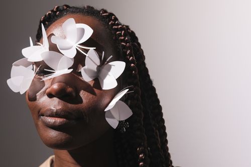 Free Close-up portrait of a woman adorned with paper butterflies on her face, creating an artistic look. Stock Photo