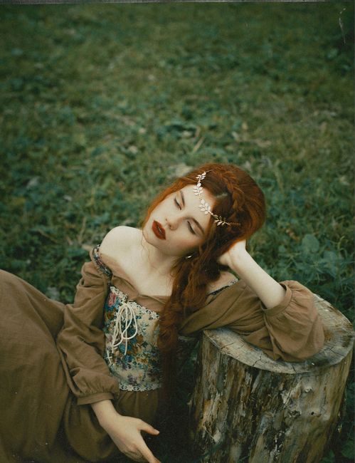 Red-haired woman in boho style gown relaxing outdoors in Moscow setting.