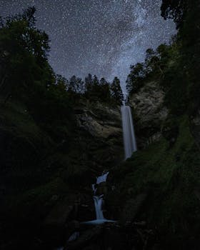 A breathtaking view of a waterfall under a starry night sky in Walenstadt, Switzerland.