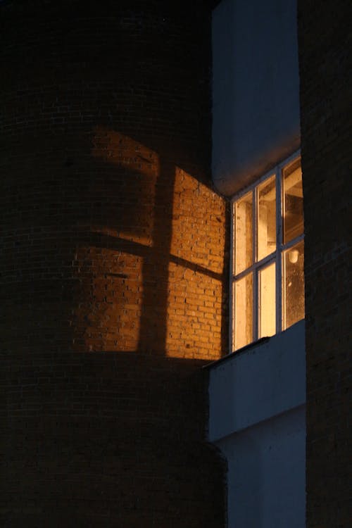 A Light Casting a Shadow of Rectangular Shapes on  a Brown  Brick Wall