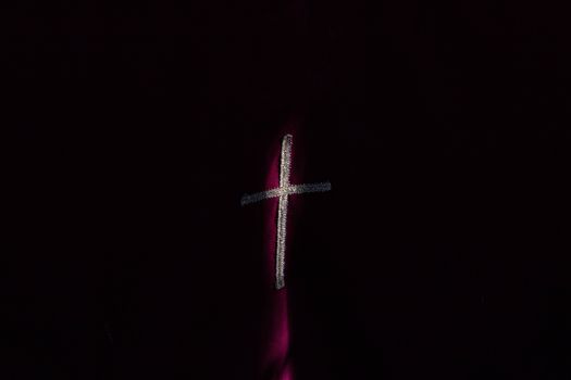 An abstract depiction of a cross on a dark background with moody lighting.