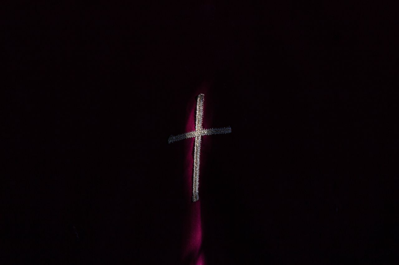 an abstract depiction of a cross on a dark background with moody light