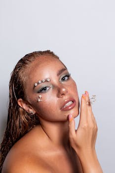Close-up portrait of a woman with creative floral makeup and freckles on a studio white background.